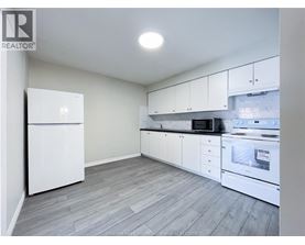A kitchen with white appliances and cabinets.