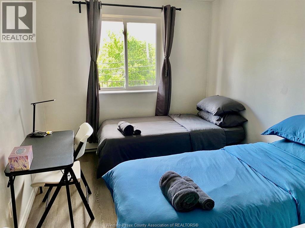 A bedroom with a blue bed and a small table with a chair.