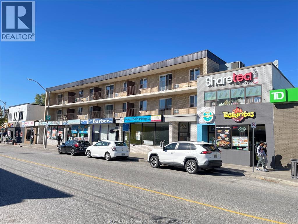 A street view with cars parked and a building with a Share Tea sign.