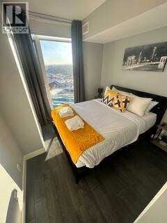 A bedroom with a large bed and a window overlooking a cityscape.