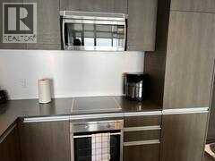 A stainless steel kitchen with a Realty sign on the wall.