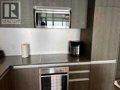 A stainless steel kitchen with a Realty sign on the wall.