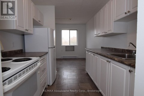 A kitchen with white cabinets and a white stove top oven.