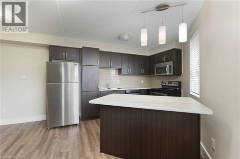 A kitchen with a stainless steel refrigerator and wooden cabinets.
