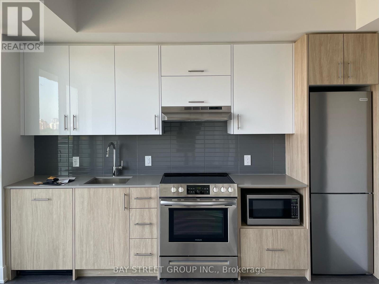 A modern kitchen with white cabinets and stainless steel appliances.