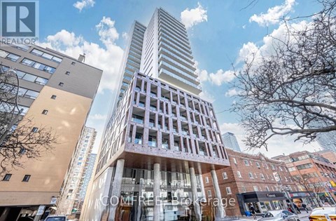A tall building with a unique design stands out in a city street.