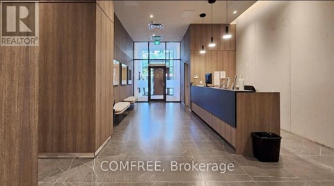 A reception area with a wooden wall and a black trash bin.