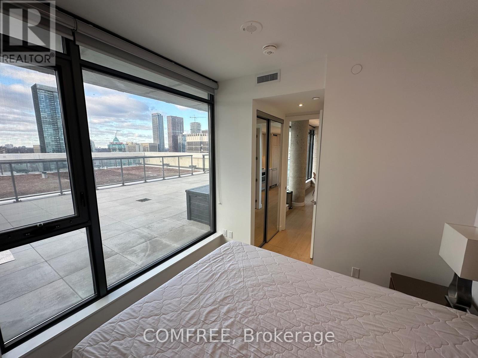 A bedroom with a large bed and a view of the city through the window.