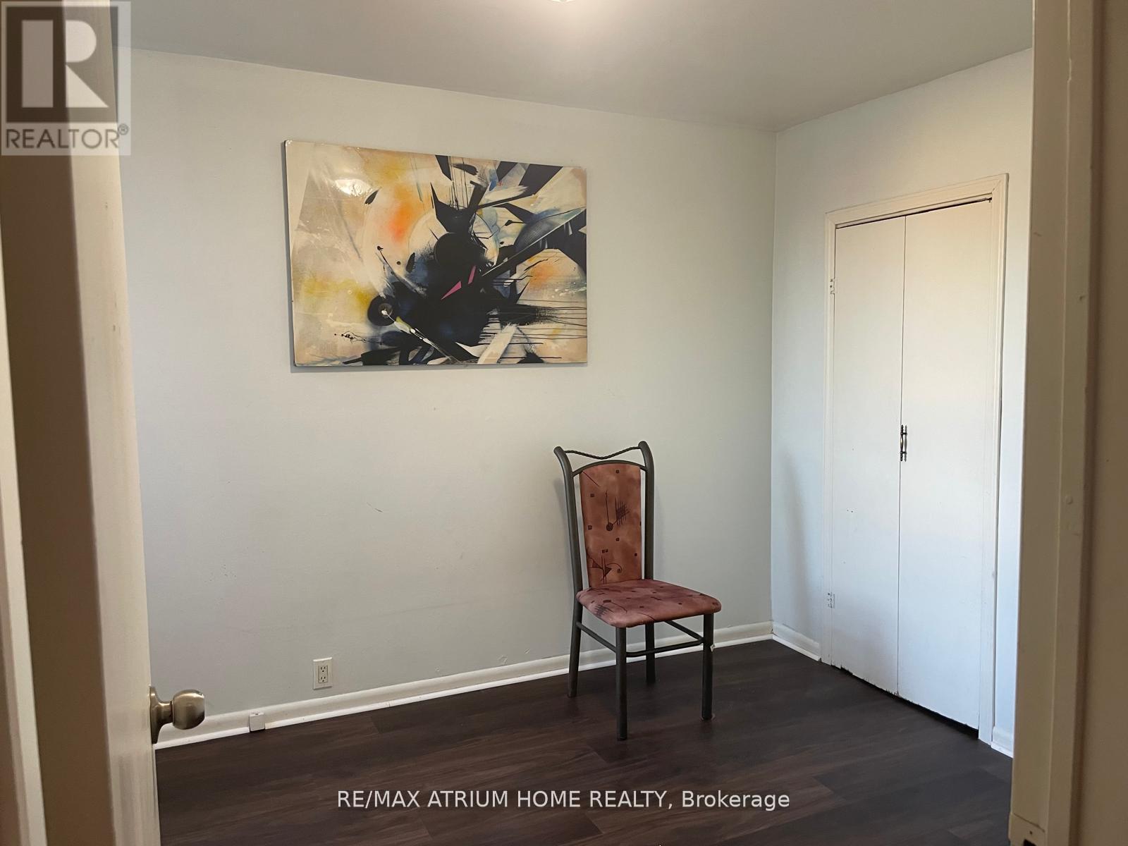 A room with a chair and a painting on the wall.