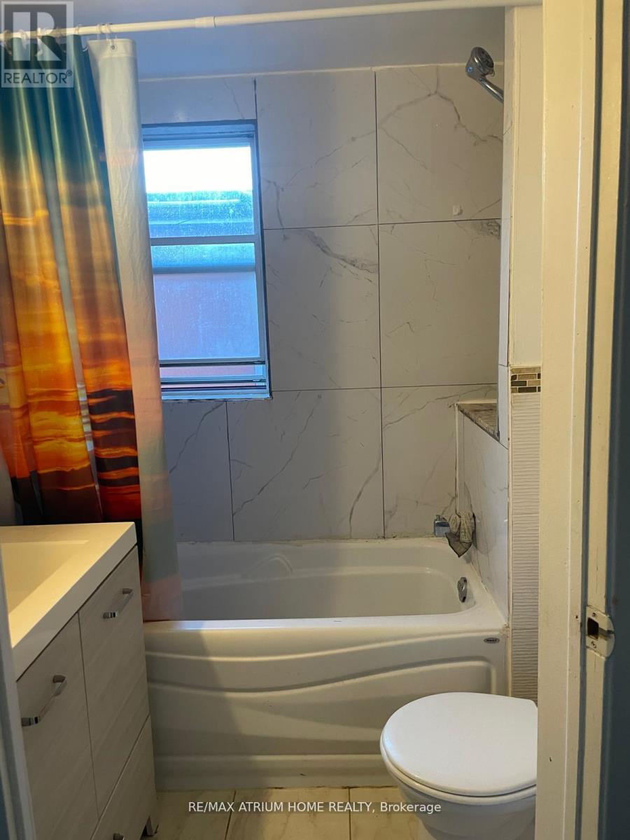 A bathroom with a bathtub, toilet, and a window.