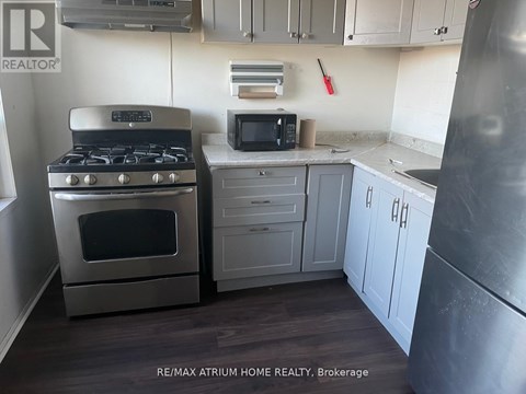 A kitchen with a stove, microwave, and refrigerator.