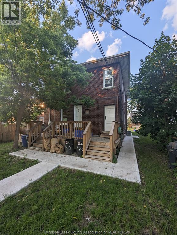 A house with a wooden deck and a tree in front.