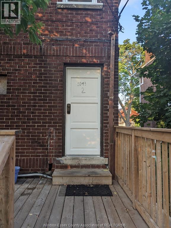 A white door with the number 1043 on it is on a brick building.