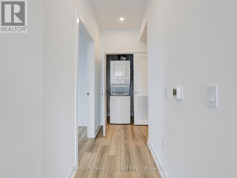 A modern kitchen with white cabinets and a wooden floor.