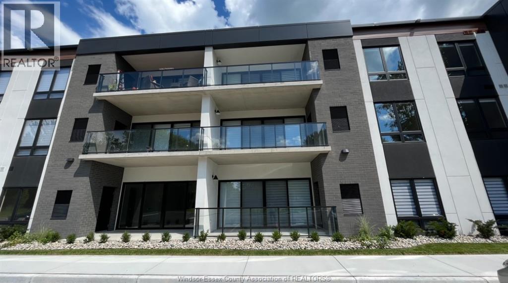 A modern apartment building with a balcony and a garden in front.