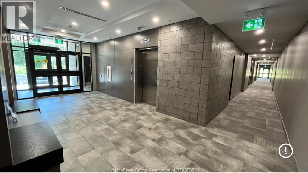A hallway with a tiled floor and a green exit sign above the door.