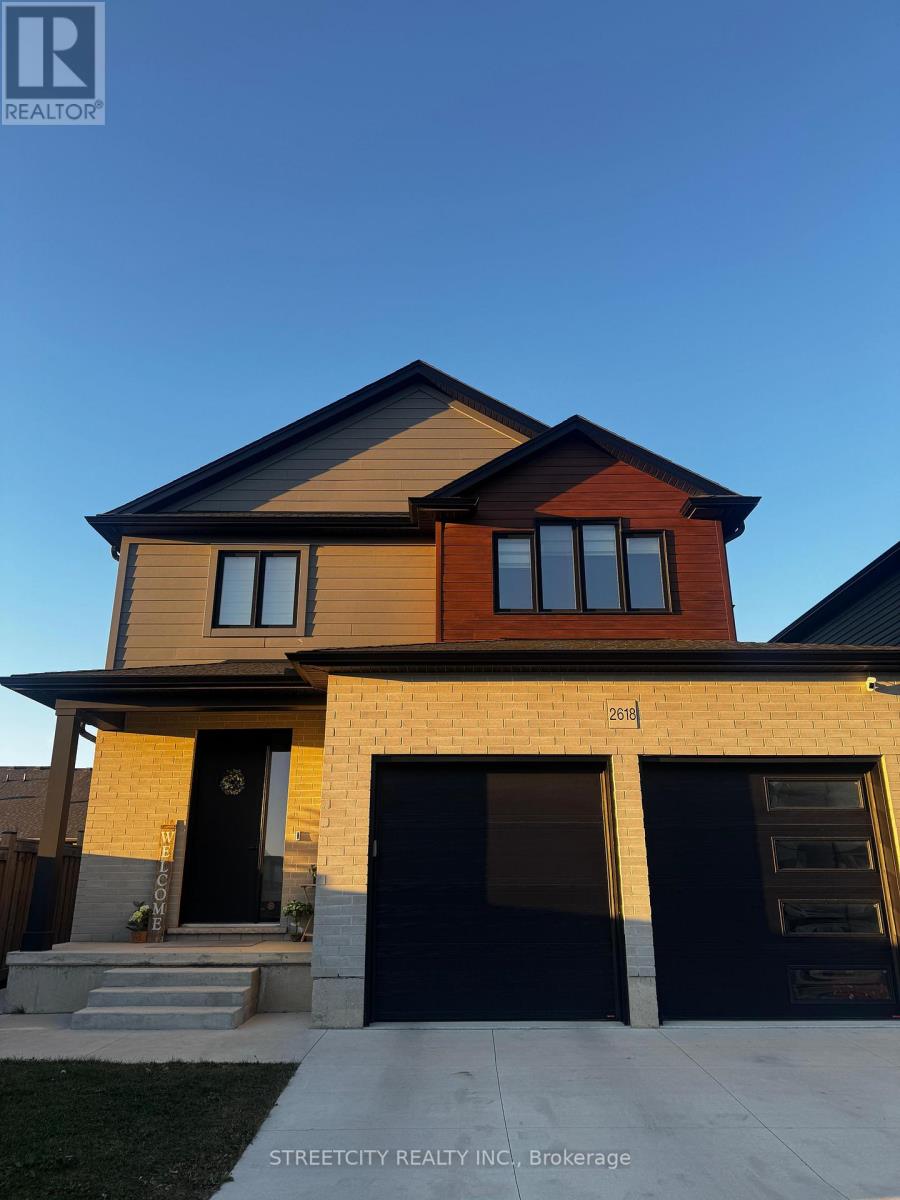 A modern two-story house with a black garage door is for sale.