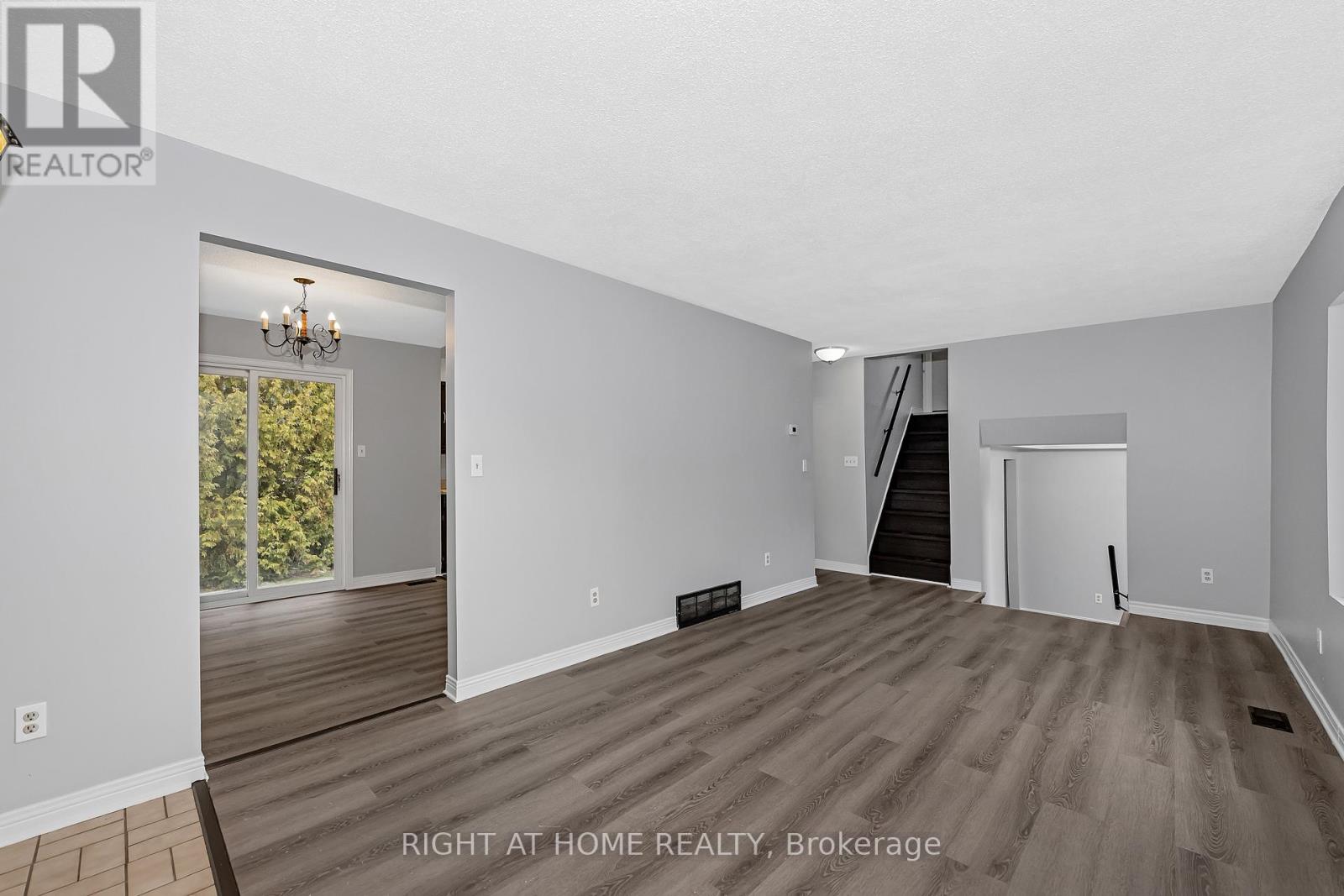 A spacious room with wooden flooring and white walls, with a door leading to a balcony.