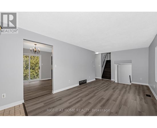 A spacious room with wooden flooring and white walls, with a door leading to a balcony.