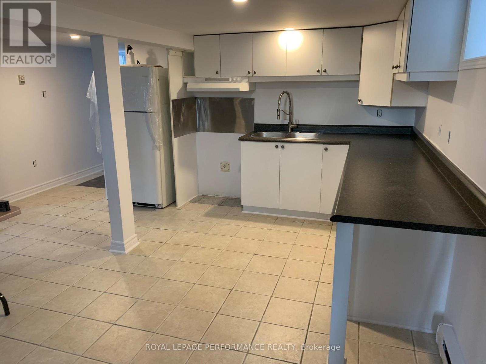 A kitchen with white cabinets and a black countertop.