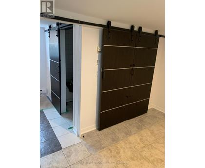 A brown wardrobe with black handles is in a room with a white door.