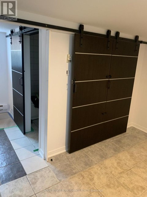 A brown wardrobe with black handles is in a room with a white door.