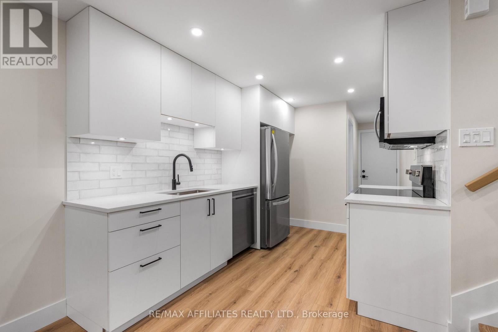 A modern kitchen with white cabinets and a stainless steel refrigerator.