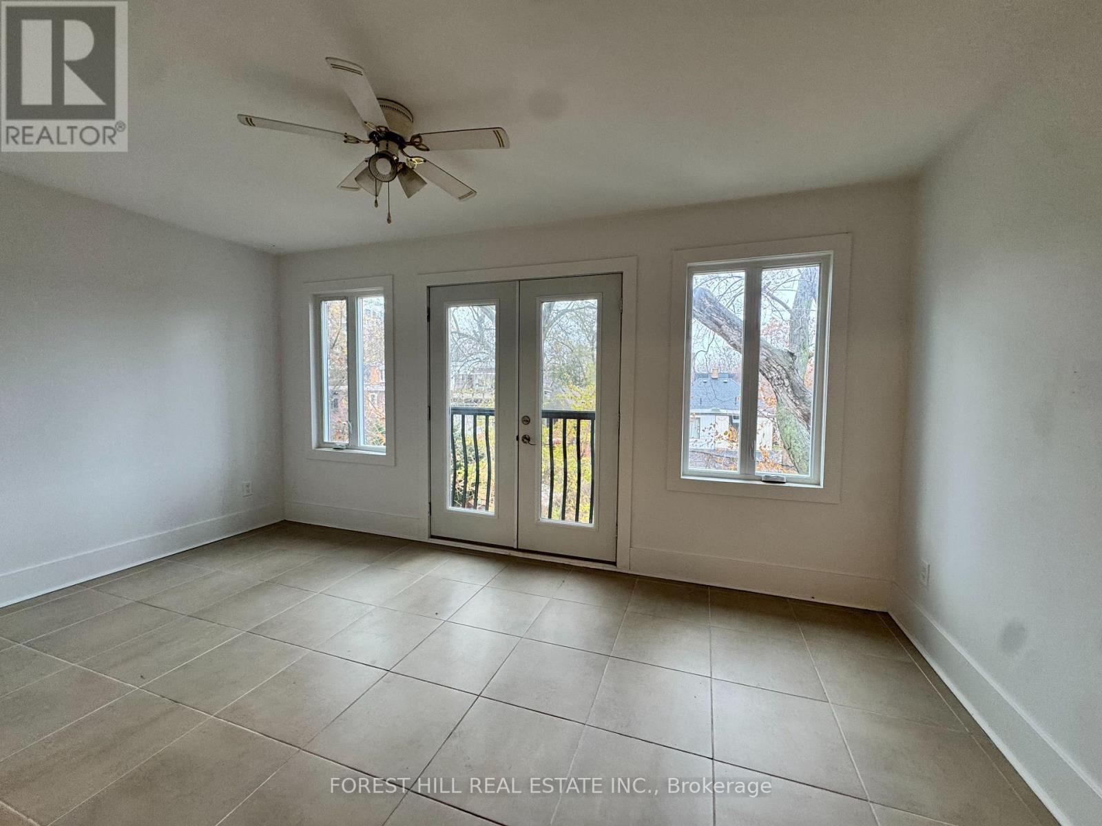 A spacious room with a ceiling fan and sliding glass doors.