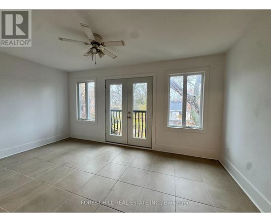 A spacious room with a ceiling fan and sliding glass doors.