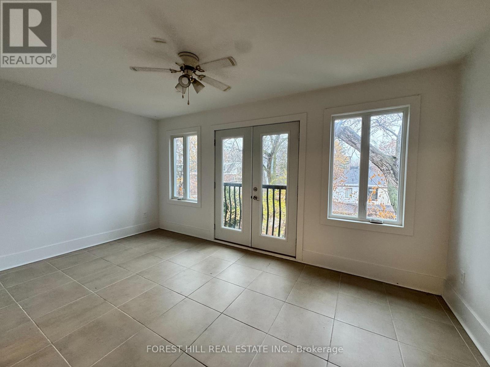 A room with a ceiling fan and tiled flooring.