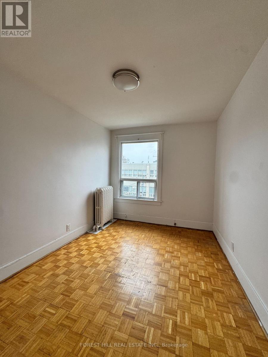 A room with wooden flooring and a window with a view of a building outside.