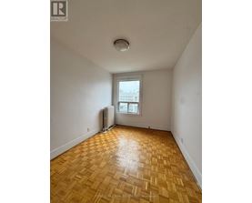 A room with wooden flooring and a window with a view of a building outside.