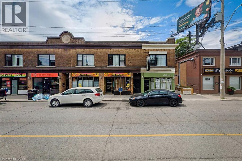 A street view with cars parked and a building with a REALTOR sign.