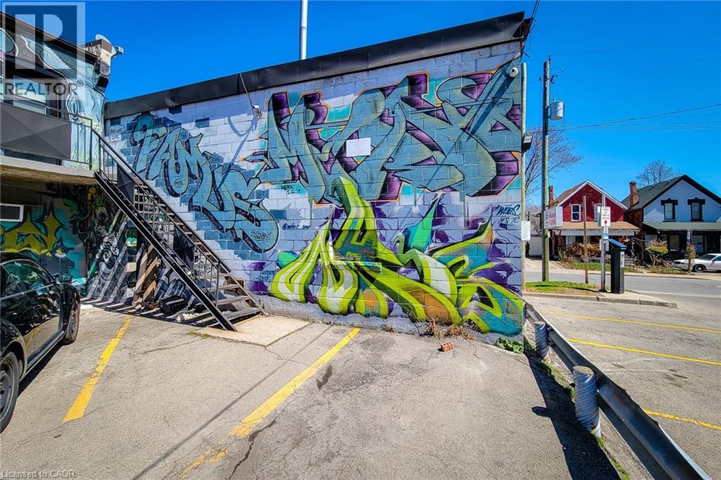 A wall covered in graffiti art is seen in the foreground with a car parked in front.