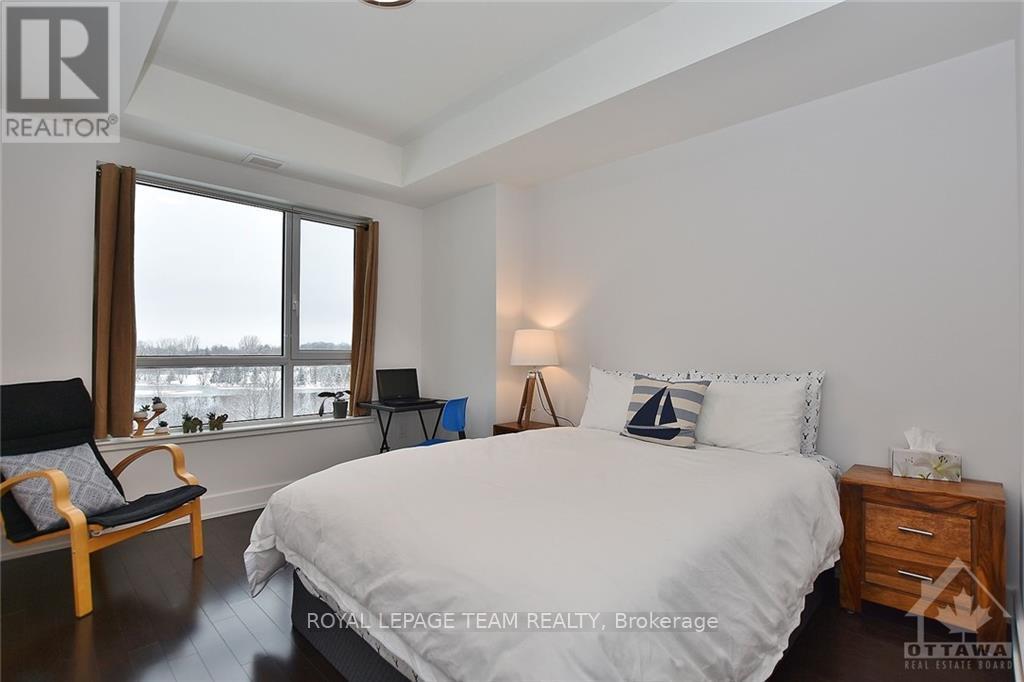 A bedroom with a large bed, a chair, and a window.