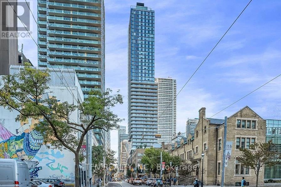 A city street with a mix of modern and older buildings, with people walking on the sidewalk.