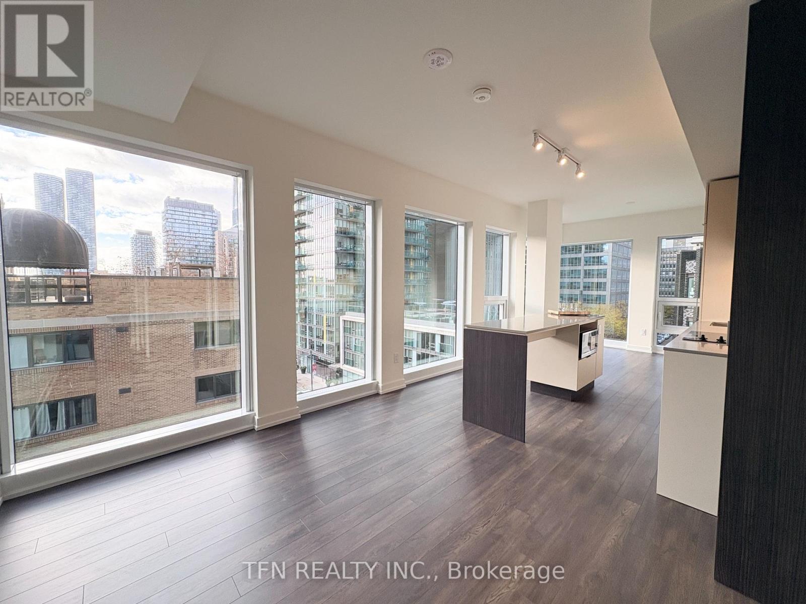 A spacious room with a view of the city skyline through large windows.