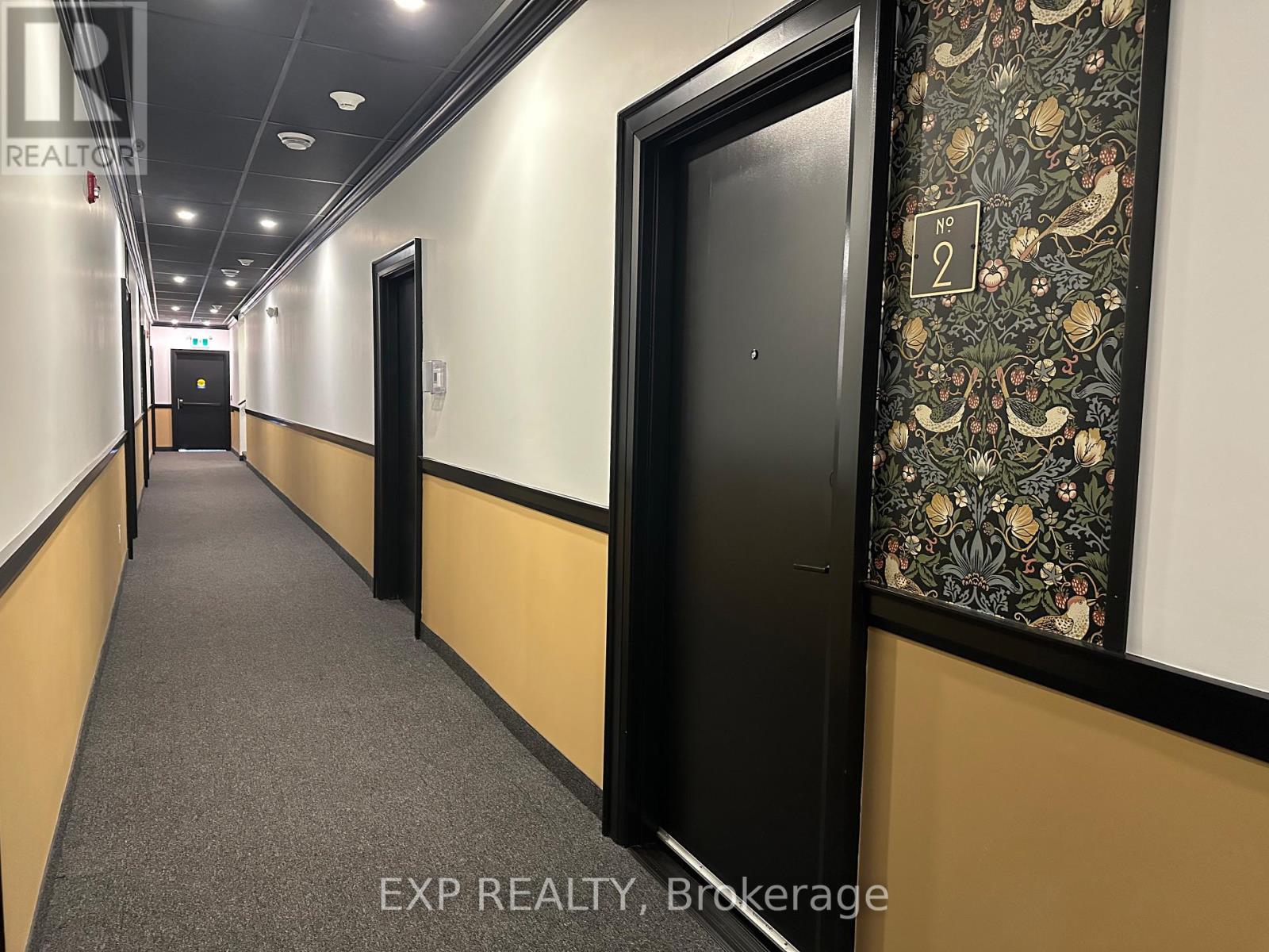 A hallway with doors on both sides and a wallpapered wall on the right.