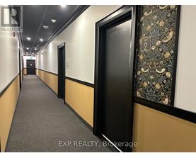 A hallway with doors on both sides and a wallpapered wall on the right.
