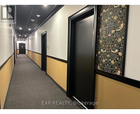 A hallway with doors on both sides and a wallpapered wall on the right.