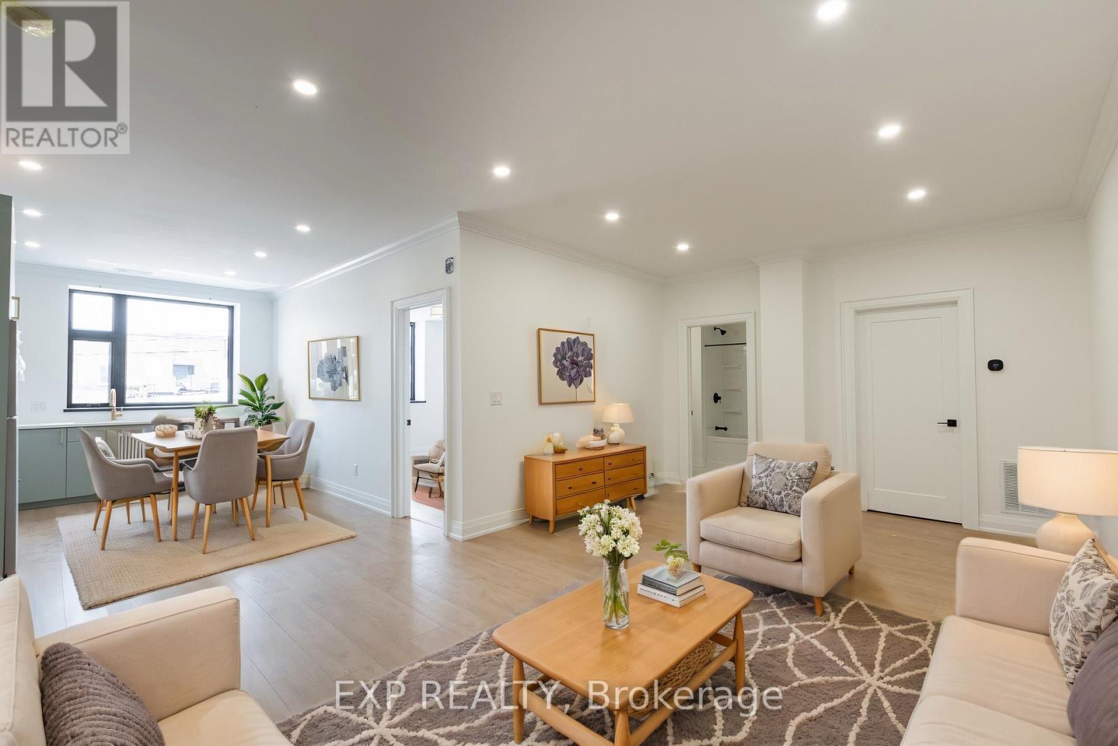 A well-lit, spacious living room with a dining area in the background.