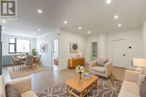 A well-lit, spacious living room with a dining area in the background.