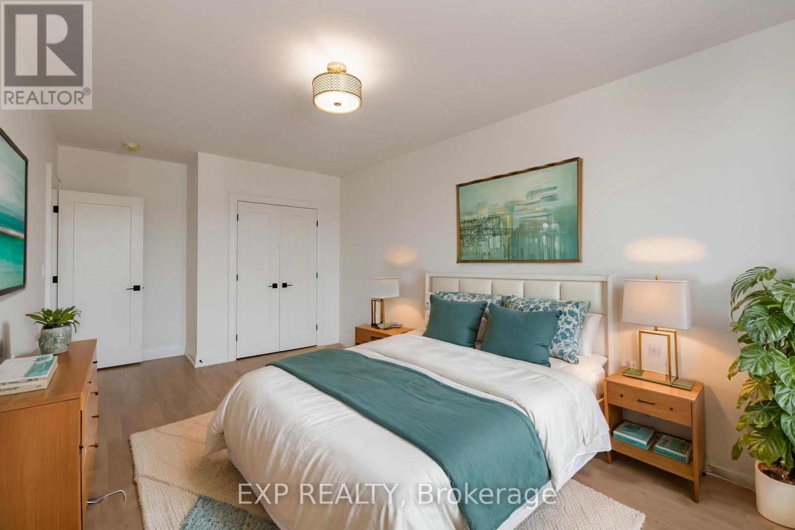 A bedroom with a bed, nightstands, and a plant.