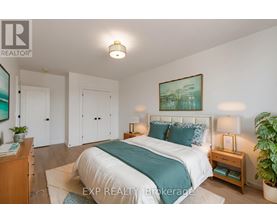A bedroom with a bed, nightstands, and a plant.