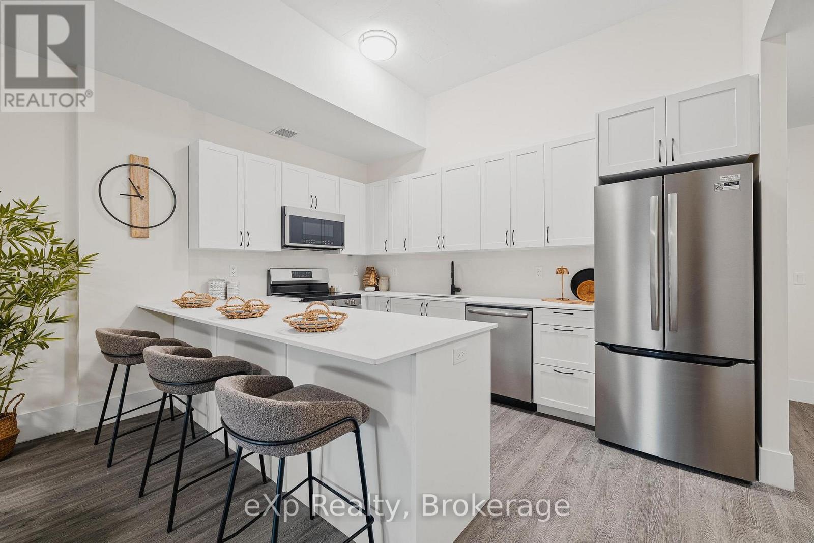 A kitchen with white cabinets and a stainless steel refrigerator.