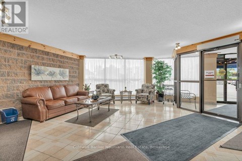 A living room with a brown leather couch and a glass table.