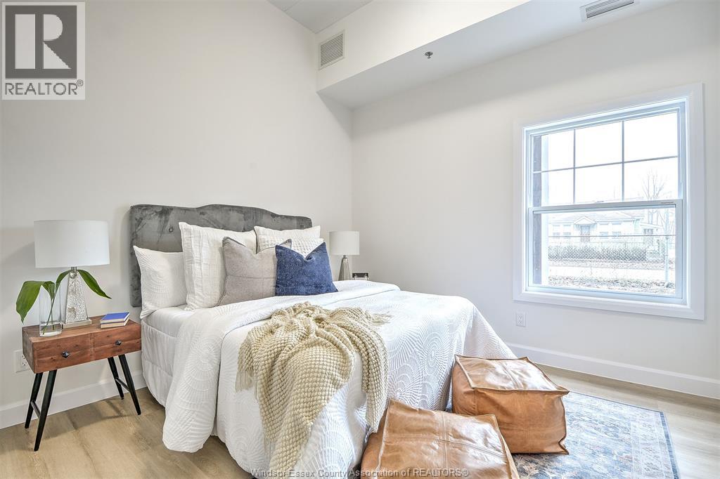 A bedroom with a large bed and a small table with a lamp.