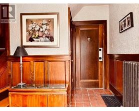 A hallway with a wooden door and a framed picture on the wall.