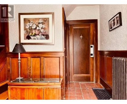 A hallway with a wooden door and a framed picture on the wall.