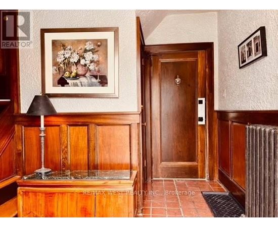 A hallway with a wooden door and a framed picture on the wall.
